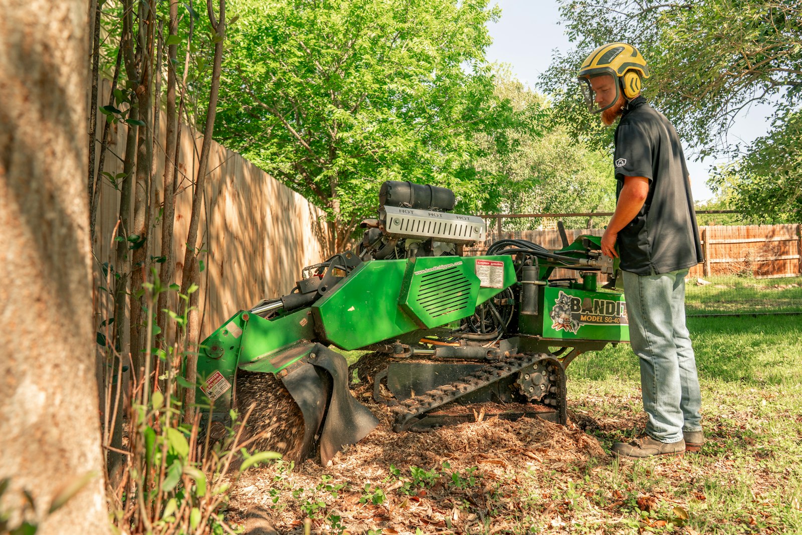 A worker operating a stump grinder in a backyard
